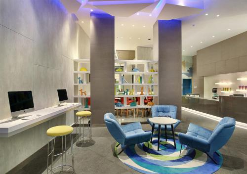 a lobby with chairs and a table and a tv at Holiday Inn Express Jakarta Wahid Hasyim by IHG in Jakarta