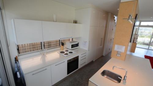 a kitchen with white cabinets and a stove top oven at Connemara Wallabi Point in Wallabi Point