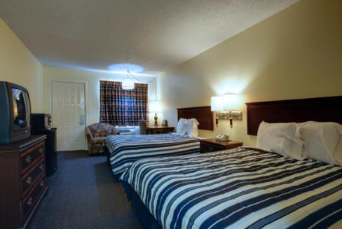 a hotel room with two beds and a television at Americas Best Value Inn Comanche in Comanche