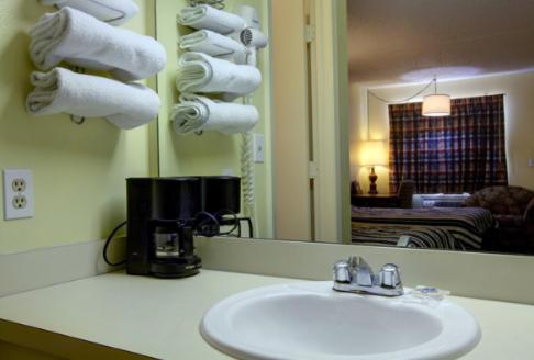 a bathroom with a sink and a mirror and towels at Americas Best Value Inn Comanche in Comanche