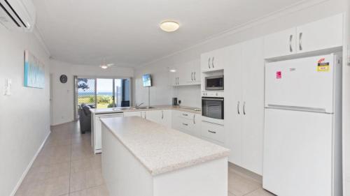 a kitchen with white cabinets and a white refrigerator at Apartment 19 - The Meridian in Old Bar