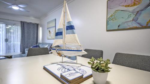 a toy sailboat on a table with a book at Apartment 27 - The Meridian in Old Bar