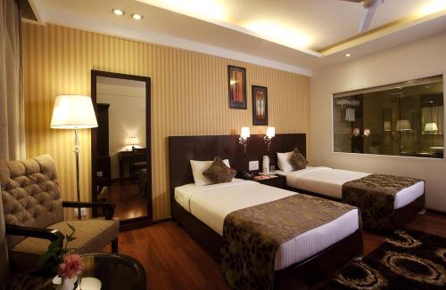 a hotel room with two beds and a chair at ASIA The HERITAGE in Jammu