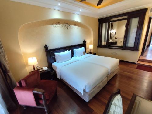a bedroom with a large white bed and a chair at Casa del Rio Melaka in Melaka