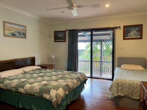 1 Schlafzimmer mit 2 Betten und einer Glasschiebetür in der Unterkunft Cooloola Cottage Rainbow Beach in Rainbow Beach