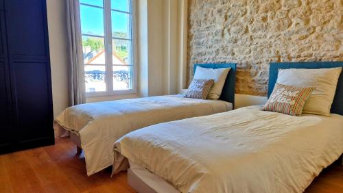 zwei Betten in einem Zimmer mit einer Ziegelwand in der Unterkunft L'Arromanchaise - Gold Beach in Arromanches-les-Bains