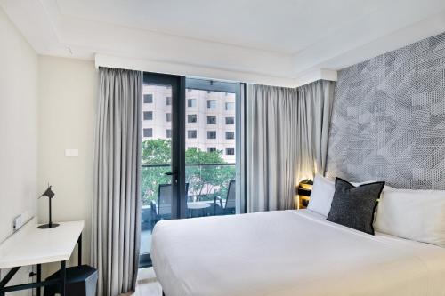 a hotel room with a bed and a desk and a window at Kith Hotel Darling Harbour in Sydney