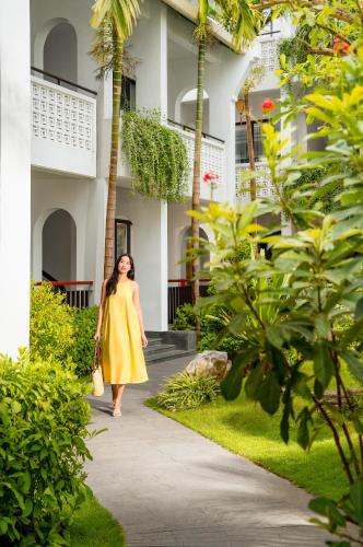 a woman in a yellow dress walking down a sidewalk at The Saga Hotel Hoi An in Hoi An