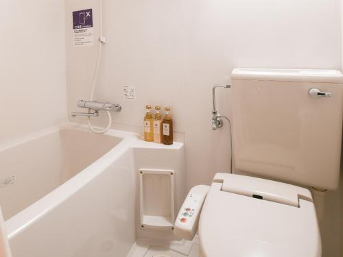 a white bathroom with a toilet and a bath tub at Vessel Hotel Fukuoka Kaizuka in Fukuoka