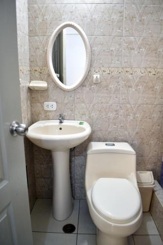 a bathroom with a toilet and a sink and a mirror at Hospedaje El Buen Samaritano in Paracas
