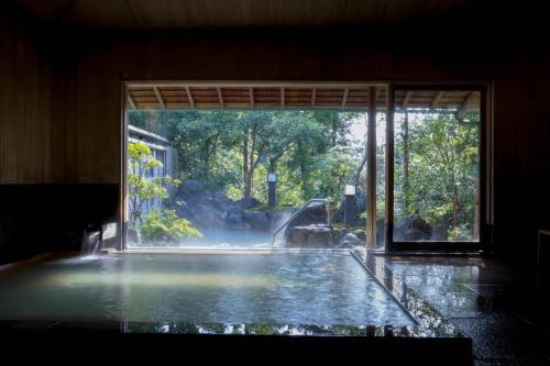 una piscina d'acqua in una stanza con finestra di Hanzuiryo a Unzen