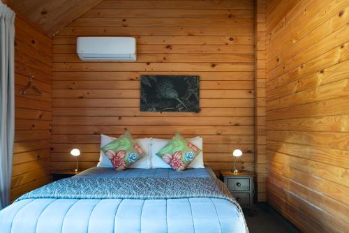 a bedroom with a bed in a wooden wall at Fox Glacier Lodge in Fox Glacier