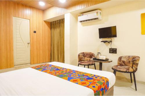 プネにあるFabExpress Gargi Executiveのベッド1台、椅子2脚、テレビが備わる客室です。