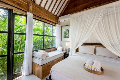 een slaapkamer met een bed en een groot raam bij Nido Boutique Cottage by BaliSuperHost in Canggu