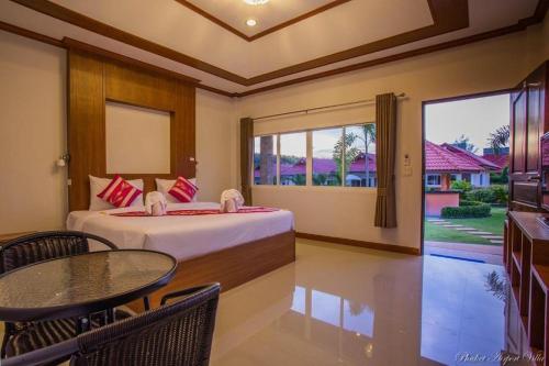 a bedroom with a bed and a table and a window at Phuket Airport Villa in Phuket Town