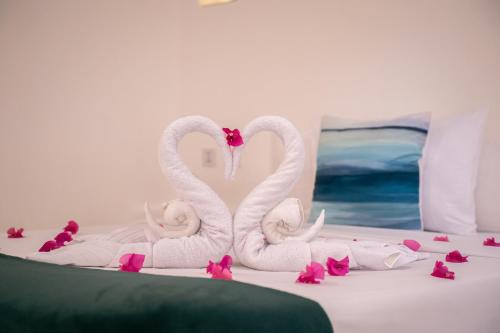 two swans sitting on a bed with pink flowers at Secret paradise moalboal in Moalboal