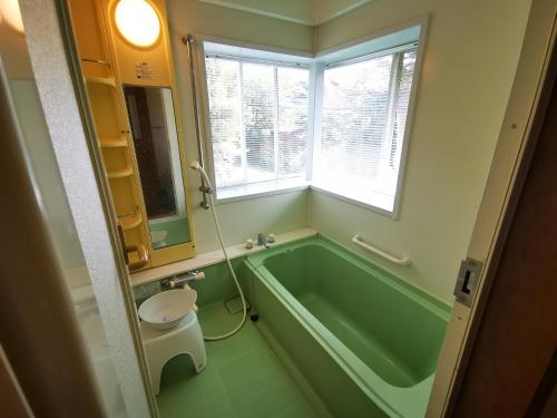 a bathroom with a green bath tub and a window at 100泊で完成する民泊 in Takamori