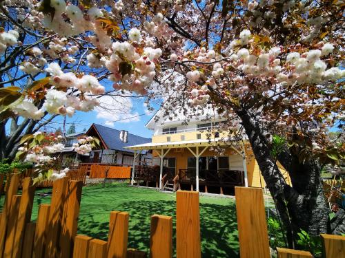 een wit huis met een hek en een boom bij 100泊で完成する民泊 in Takamori