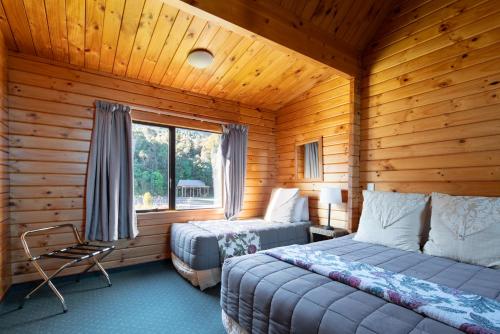 a bedroom with two beds in a log cabin at Fox Glacier Lodge in Fox Glacier