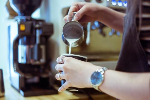 een vrouw giet koffie in een kopje bij Powder Temple in Hakuba