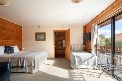 a bedroom with two beds and a balcony at Fox Glacier Lodge in Fox Glacier