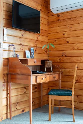 a wooden desk with a television on a wall at Fox Glacier Lodge in Fox Glacier