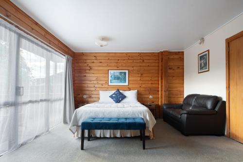 1 dormitorio con 1 cama y silla de cuero en Fox Glacier Lodge, en Fox Glacier