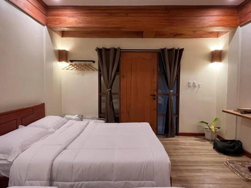 a bedroom with a large white bed and wooden floors at Tabularasa - T Luxury Boutique in New Agutaya