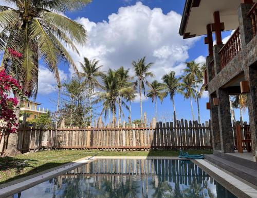 a fence with palm trees in front of a swimming pool at Tabularasa - T Palawan in San Vicente