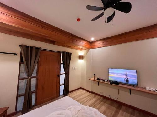 a bedroom with a ceiling fan and a flat screen tv at Tabularasa - T Palawan in San Vicente