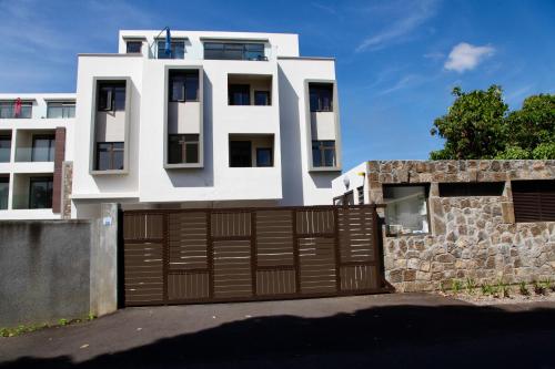 a white house with a brown garage door at Lux Penthouse Apartment 3 bedrooms Quatre Bornes in Quatre Bornes