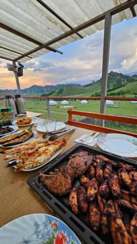a table topped with plates of food and meat at Magic Rock Tourist Camp in Nalayh