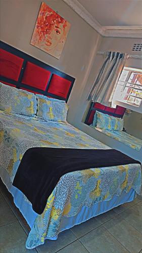 a bedroom with a bed with a blue comforter and a window at DREAMLAND GUEST HOUSe in Mahikeng