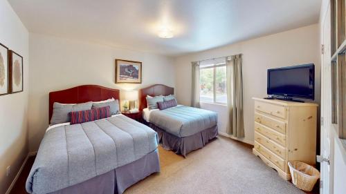 a bedroom with two beds and a flat screen tv at Henning's Escape #3328 in Moab