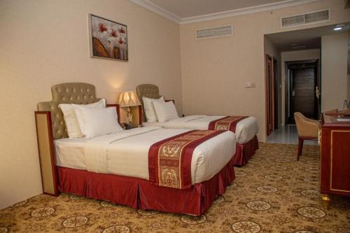 a hotel room with two beds and a desk at Al Salam Grand Hotel & Resort in Al Buraymī