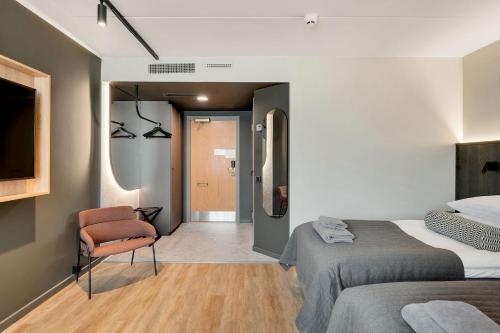 a bedroom with two beds and a chair and a mirror at Original Sokos Hotel Vaakuna Mikkeli in Mikkeli