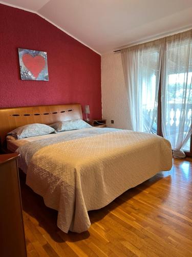une chambre avec un grand lit avec un mur rouge dans l'établissement Apartment Peloža 1, à Poreč