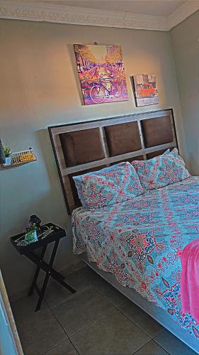 a bedroom with a bed and a side table at DREAMLAND GUEST HOUSe in Mahikeng
