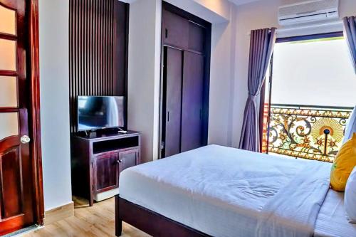 a bedroom with a bed and a tv and a window at The Palms Hotel in Ấp Bình Hưng