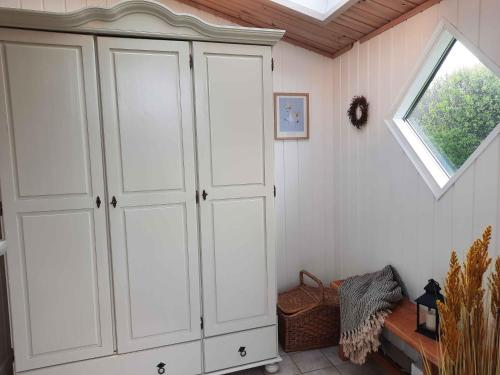 Cozy Summer House In Lnstrup For 5 People, في لونستروب: خزانة بيضاء في غرفة مع نافذة