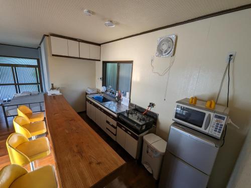 a kitchen with a table and a microwave at くじらの家 in Amami