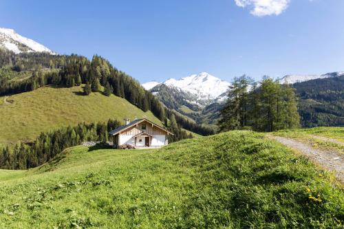 ein Haus an der Seite eines grasbewachsenen Hügels in der Unterkunft Alpengasthof Karalm in Rauris