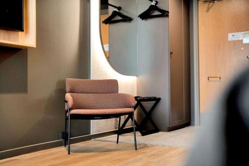 a chair sitting in a room with a mirror at Original Sokos Hotel Vaakuna Mikkeli in Mikkeli
