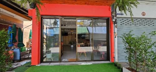 a store front with red trim and green grass at Before We Go Hostel Donmueang in Ban Ko