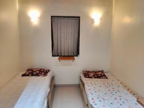 2 camas en una habitación pequeña con ventana en Luxurious 2BHK villa with garden, en Solapur
