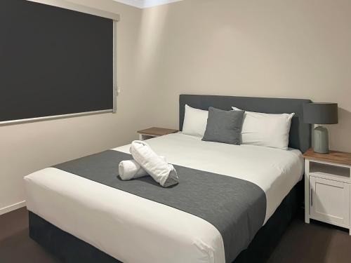 um quarto com uma grande cama branca e uma grande janela em Direct Collective - Villas on Rivergum em Emerald