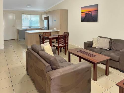 een woonkamer met een bank en een tafel bij Direct Collective - Villas on Rivergum in Emerald