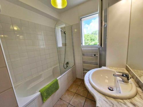 La salle de bains est pourvue d'un lavabo, d'une baignoire et d'une fenêtre. dans l'établissement L'Appart les Hauts de Sarlat, à Sarlat-la-Canéda