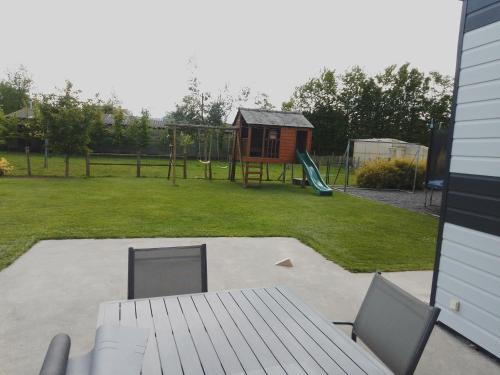 une cour avec une aire de jeux avec une structure de jeu dans l'établissement Maison 15 min du Mont St Michel, à Saint-James