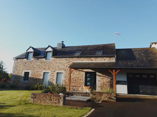 un chat assis sur le porche d'une maison en briques dans l'établissement Maison 15 min du Mont St Michel, à Saint-James